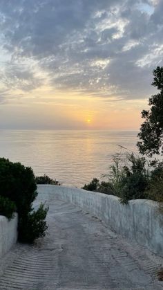 the sun is setting over the ocean and there are steps going up to the beach