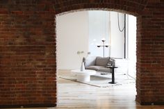 a living room with brick walls and white furniture in the center, as seen through an open doorway