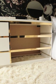 a white dresser with gold trim and drawers