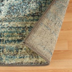 an area rug is laying on the floor next to a wooden floor with a blue and gray color scheme