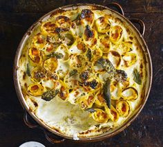 a casserole dish with cheese and vegetables in it on a wooden table top