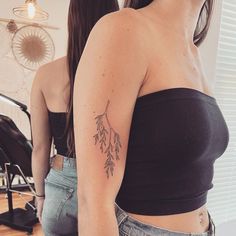 a woman with a tattoo on her left arm is looking at herself in the mirror