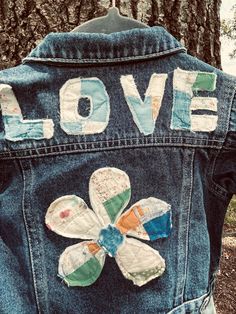 the back of a jean jacket with patches and flowers on it that says love written in large letters