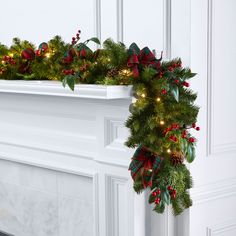 a decorated fireplace mantel with christmas garland and lights