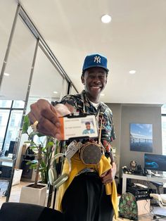 a man in a blue hat is holding up a piece of paper and some other items