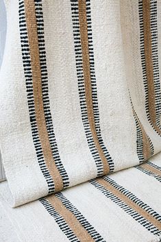 a white couch with black and tan striped fabric on it's back end, in front of a window