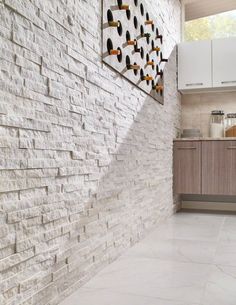 a white brick wall with shoes hanging on it's side and a kitchen in the background