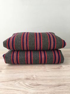 two grey and red striped pillows sitting on top of a wooden floor next to each other