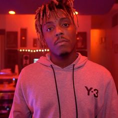 a young man with dreadlocks standing in front of a red light and looking at the camera