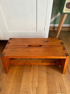 a wooden bench sitting on top of a hard wood floor next to a white door