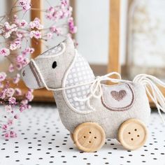 a small wooden toy horse sitting on top of a table next to some pink flowers