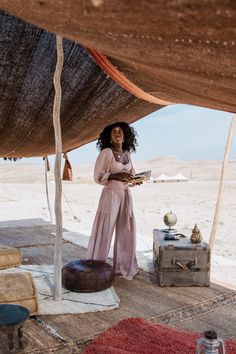 a woman standing under a tent in the desert