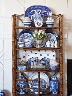 a wooden shelf filled with blue and white plates, dishes and vases on top of it