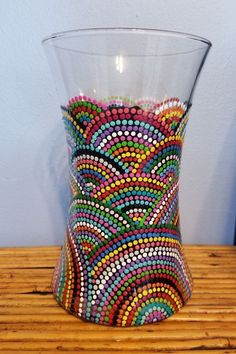 a glass with colorful beads on it sitting on a wooden table