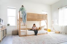 a woman sitting on top of a bunk bed next to a child in the air