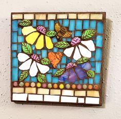 a colorful glass tile with flowers and leaves on the bottom is mounted to a wall