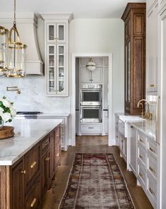 a kitchen with marble counter tops and wooden cabinets, along with a rug on the floor