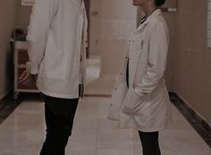 two people standing in a hallway wearing lab coats