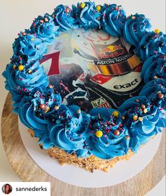 a birthday cake with blue frosting and sprinkles on the top is sitting on a wooden table