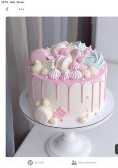 a white cake with pink and blue icing on it's top is sitting on a table