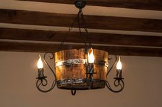 a chandelier hanging from the ceiling with three lights on each side and a wooden barrel in the middle