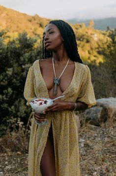 a woman in a yellow dress holding a bowl of food