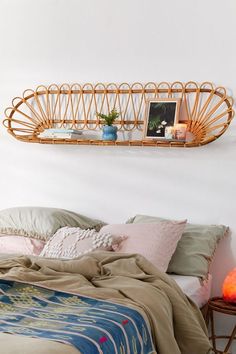 a bed with pillows and blankets on it next to a shelf that has pictures above it