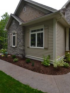 a house with landscaping in front of it and grass around the yard area on either side