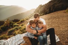 a man, woman and two children sitting on a blanket at the top of a mountain