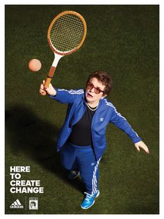 a man holding a tennis racquet on top of a grass covered field next to a ball