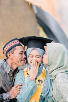 an older man and woman kissing each other in front of a graduate's cap