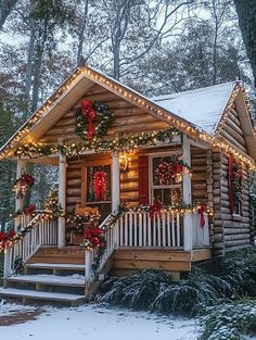 a log cabin decorated for christmas with wreaths and lights on the front porch, covered in snow