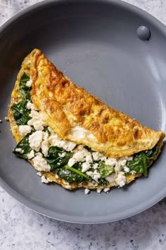 an omelet with spinach and feta cheese in a gray bowl on a marble table