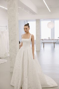 a woman standing in front of a white dress