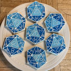 blue and white decorated cookies with numbers on them sitting on a plate next to a wooden table