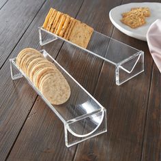 a stack of crackers sitting on top of a wooden table next to a plate of crackers