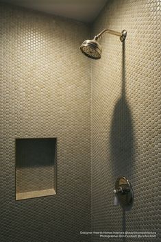 a shower head and thermostaer in a bathroom with silver tiles on the walls