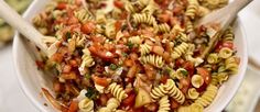 a white bowl filled with pasta salad and wooden spoons