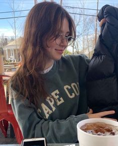 a woman sitting at a table with a bowl of food