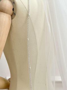 a mannequin with a white dress on it's back and silver chain