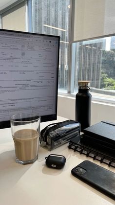 a cup of coffee sitting on top of a desk next to a computer monitor