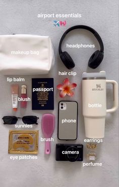 the contents of a travel bag laid out on top of a white surface with headphones and other items