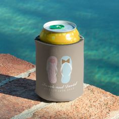 a can cooler sitting on top of a rock near the water