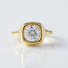 a yellow gold ring with a round brilliant cut diamond in the center, on a white background