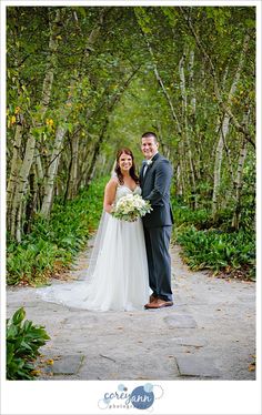 a bride and groom posing for a photo in front of some trees at their wedding