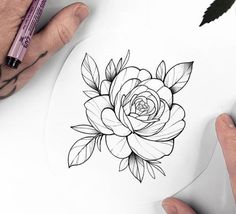 a person drawing a flower on top of a piece of paper next to a marker pen