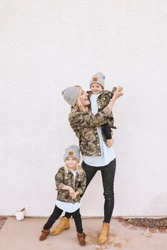 a woman and her child are standing in front of a white wall wearing winter clothes