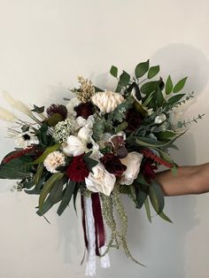 a bouquet of flowers is being held by someone's hand against a wall with white and red accents