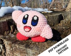 a crocheted pink stuffed animal sitting on top of a tree stump in the snow