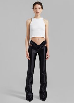 a woman wearing black leather pants and a white crop top with an open - back